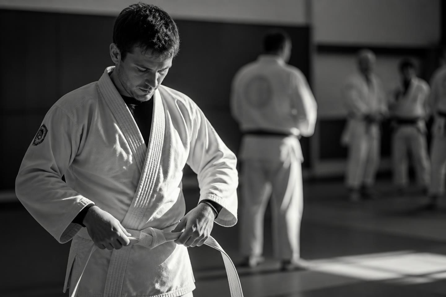 Aluno iniciante amarrando a faixa branca do kimono antes do treino de Jiu-Jitsu